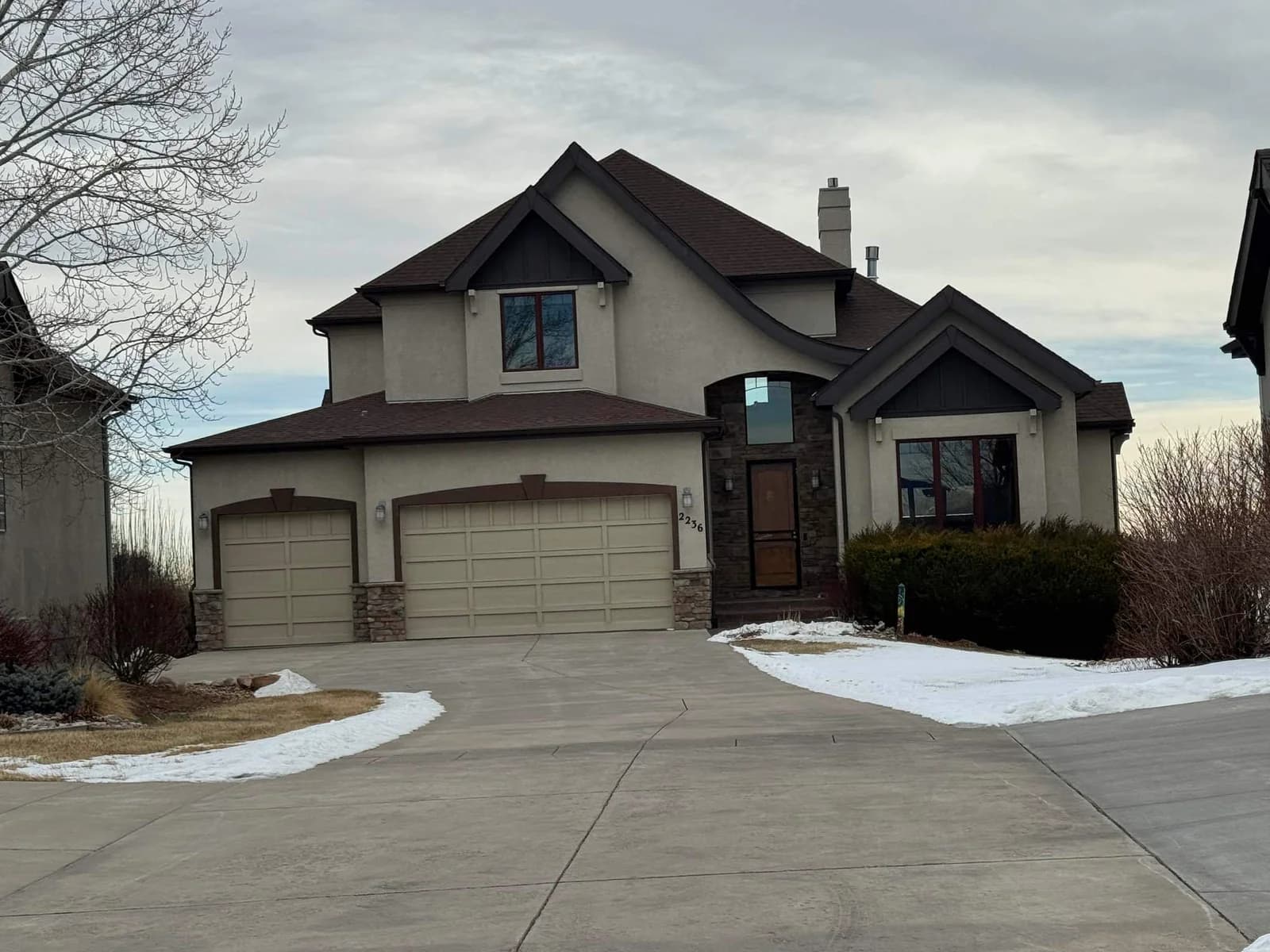Missouri two-story stucco home with three-car garage during winter storm season — documenting cold-weather roofing damage for a supplement claim