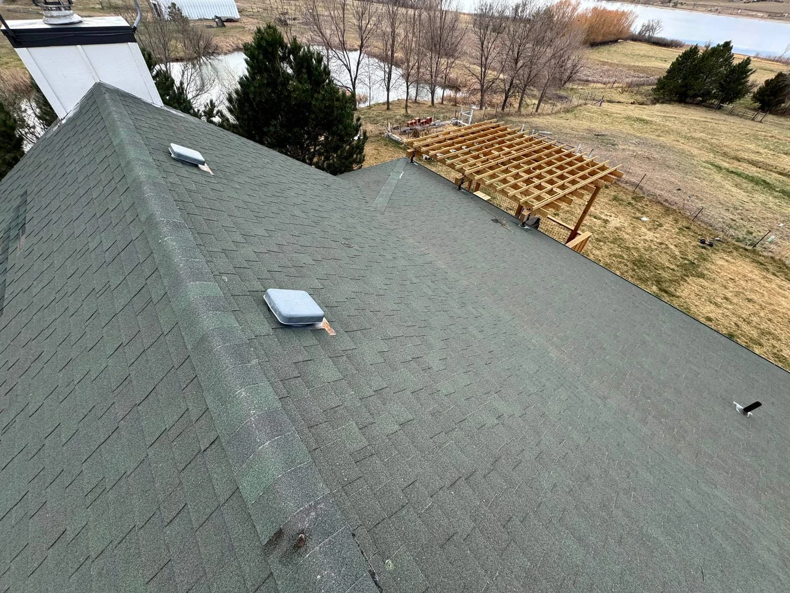 North Carolina aerial shingle roof inspection overlooking a wooded property and lake — post-storm supplement documentation