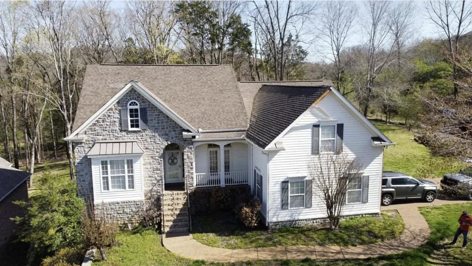 Two-story Tennessee home with mismatched roof shingles after a carrier paid for partial replacement — the scenario Tennessee's matching rule prohibits